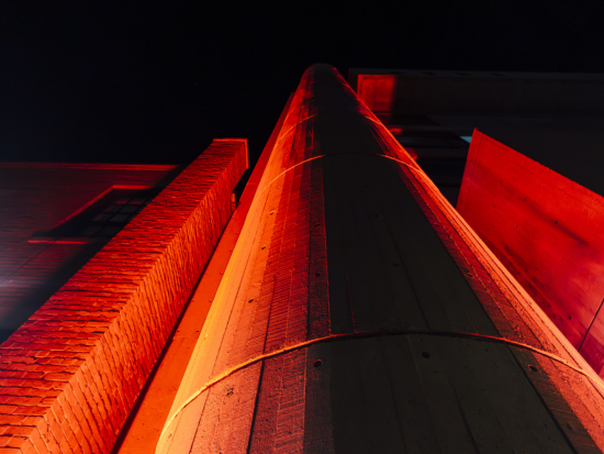 Looking up the side of 320 Newbury Street at night as a red light shines on the building.