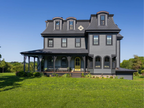 A quirky Victorian home in dark colors offset by a bright yellow door, whose facade was inspired by the Addams Family.