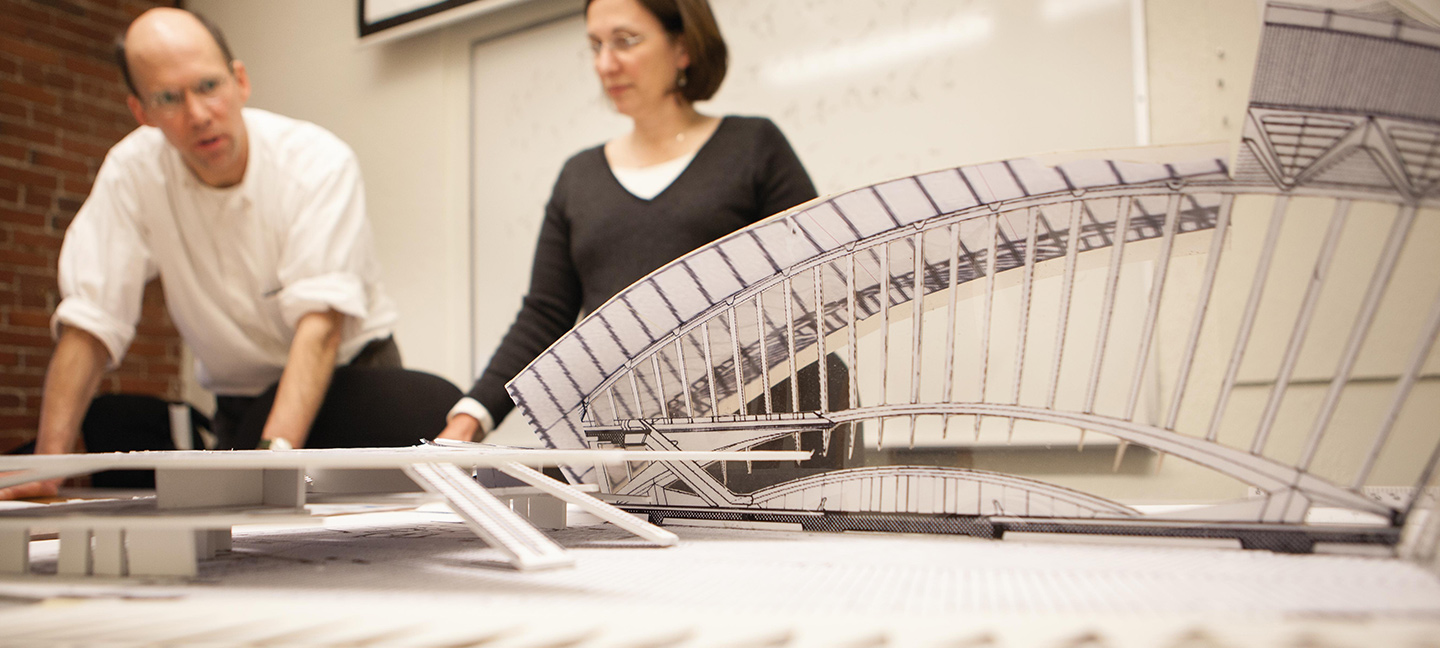 man and woman lecturing in front of architecture model