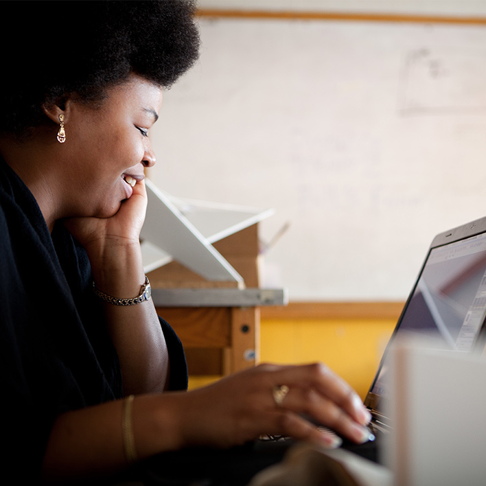 young black woman smiling at her work on computer
