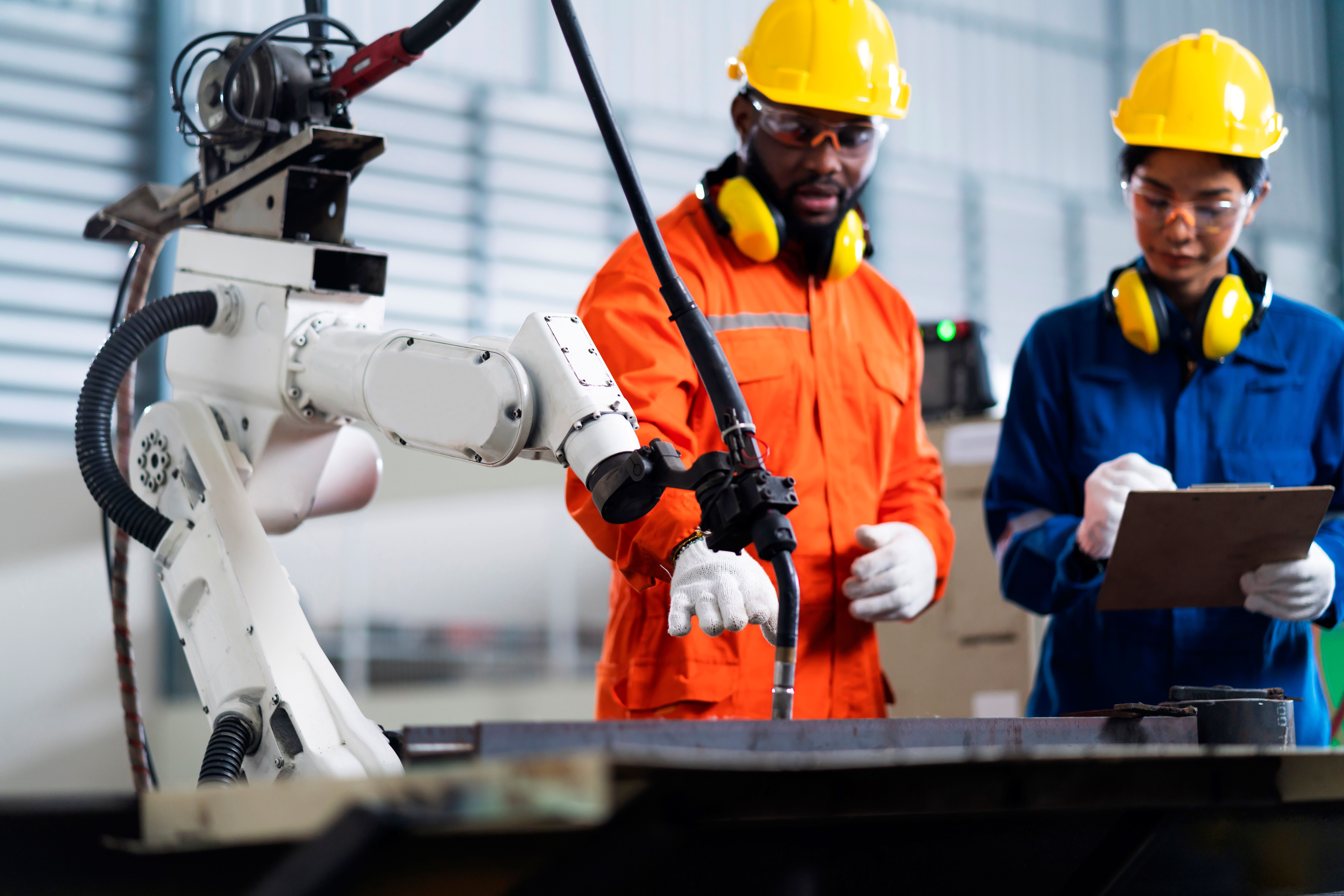 Two technicians collaborate on the robotic arm in front of them.