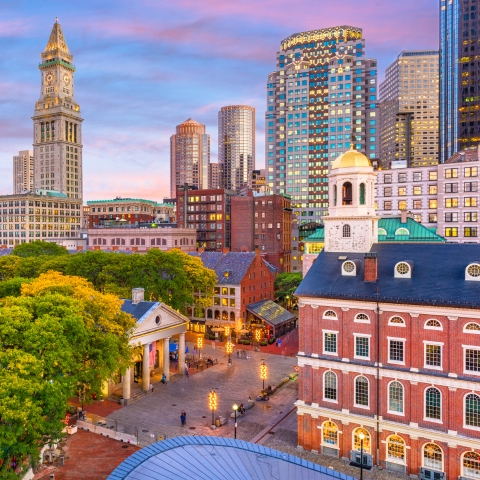 Boston skyline at sunset with historic Faneuil Hall in foreground and modern skyscrapers in background, symbolizing law and built environment.