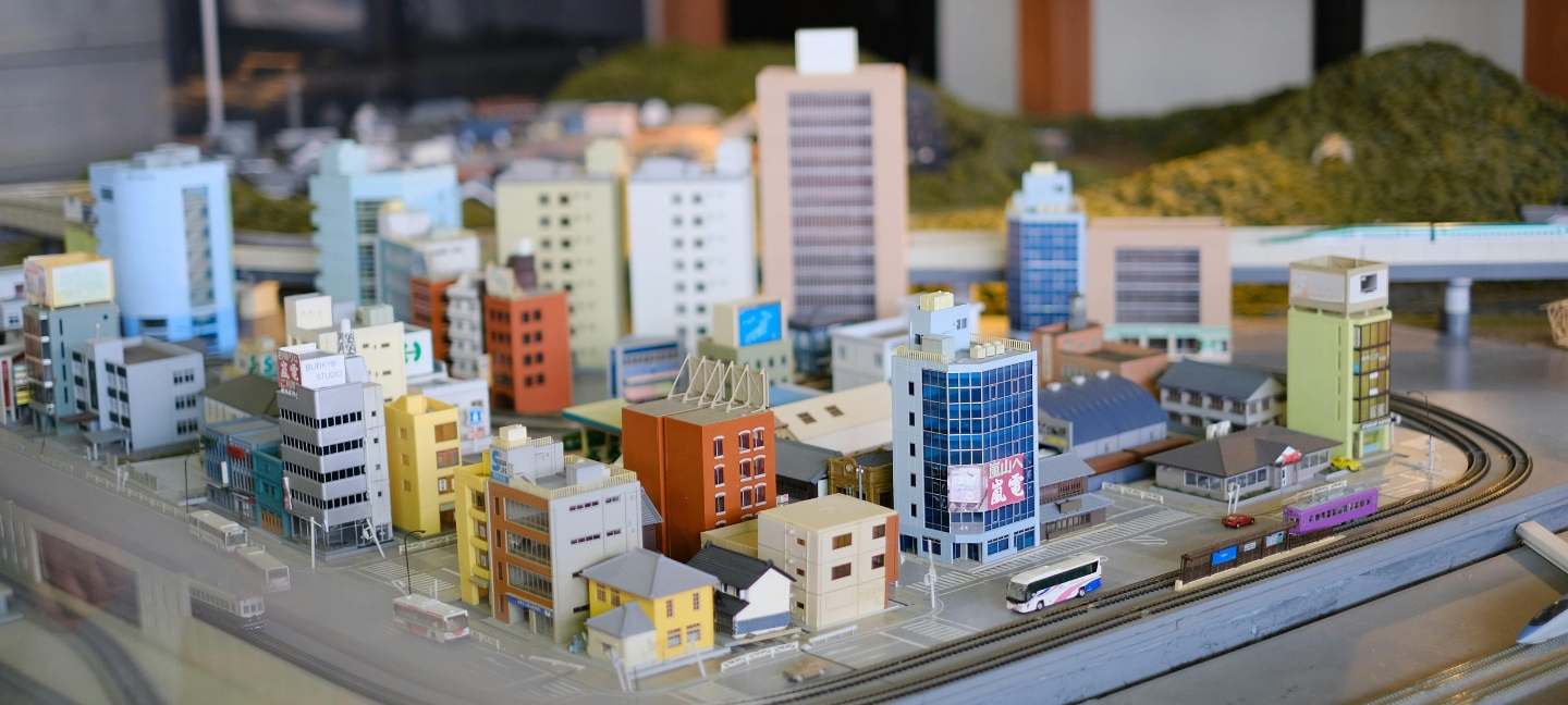 Colorful miniature city model with high-rise buildings, roads, vehicles, and railway tracks showcasing urban infrastructure and planning.