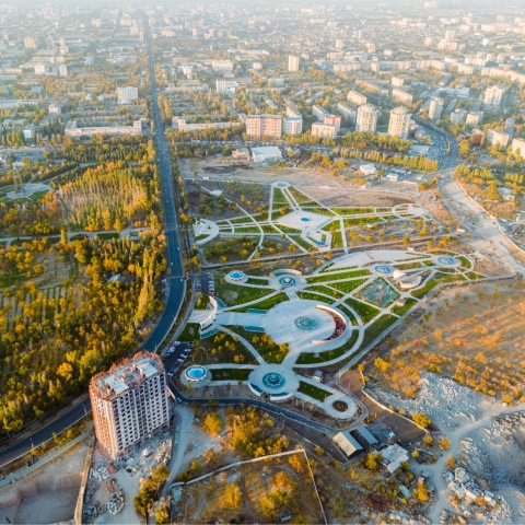 Aerial view of an urban park under development with circular plazas, green spaces, and surrounding cityscape for capstone research in design.