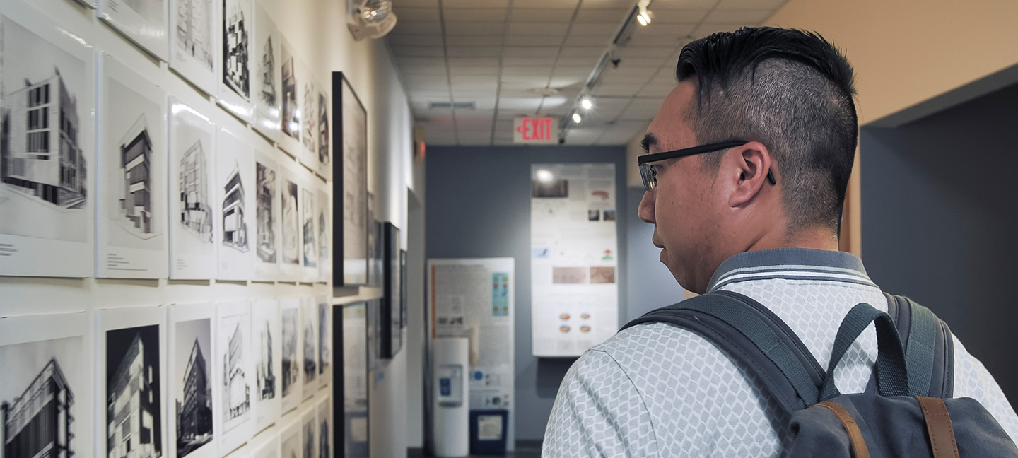 boy with backpack looking at student work on wall