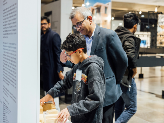 A young kid enjoys an interactive, hands-on feature of the Doshi Exhibit at the BAC McCormick Gallery while his father watches.