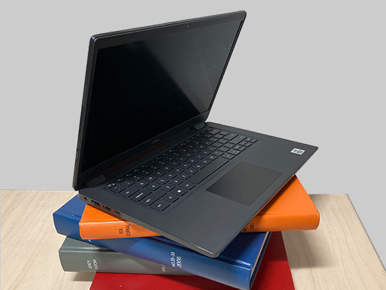 A laptop computer sitting on top of various textbooks
