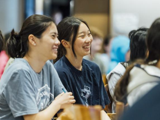 Two BAC Summer Academy students share a laugh while listening to a lecture.