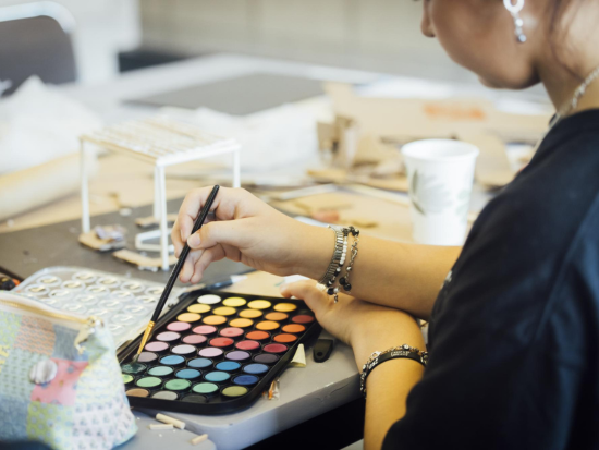 A BAC Summer Academy student collects more watercolor paint on their brush.