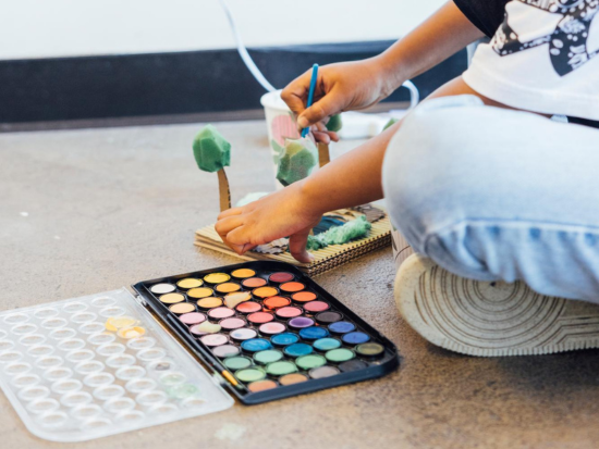 Student painting small model trees with a watercolor palette as part of a landscape or site design project in the BAC Pre-College Urban Design and Planning Studio.