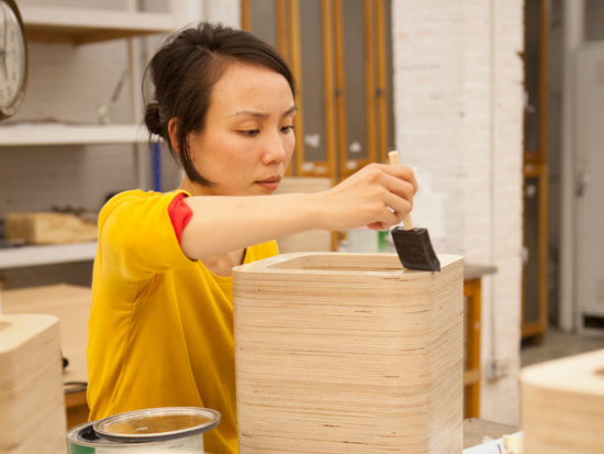 A BAC student works on staining a wood model.