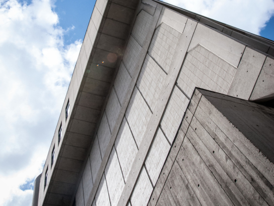 Looking up at the Boston Architectural College's Brutalist architecture at 320 Newbury Street in Boston, featuring exposed concrete and geometric forms.