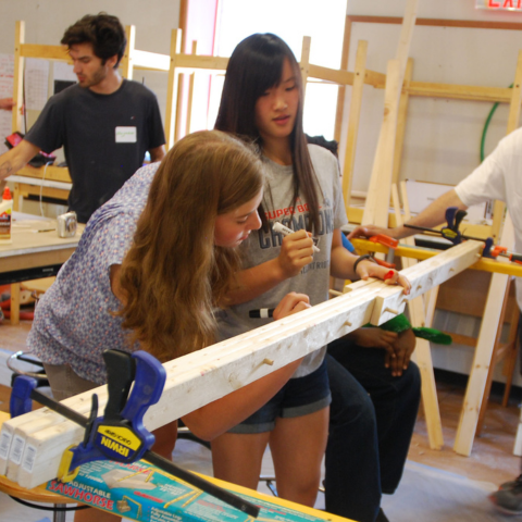 Students mark up connected pieces of 2-by-4 pieces of wood during a group project at Summer Academy.