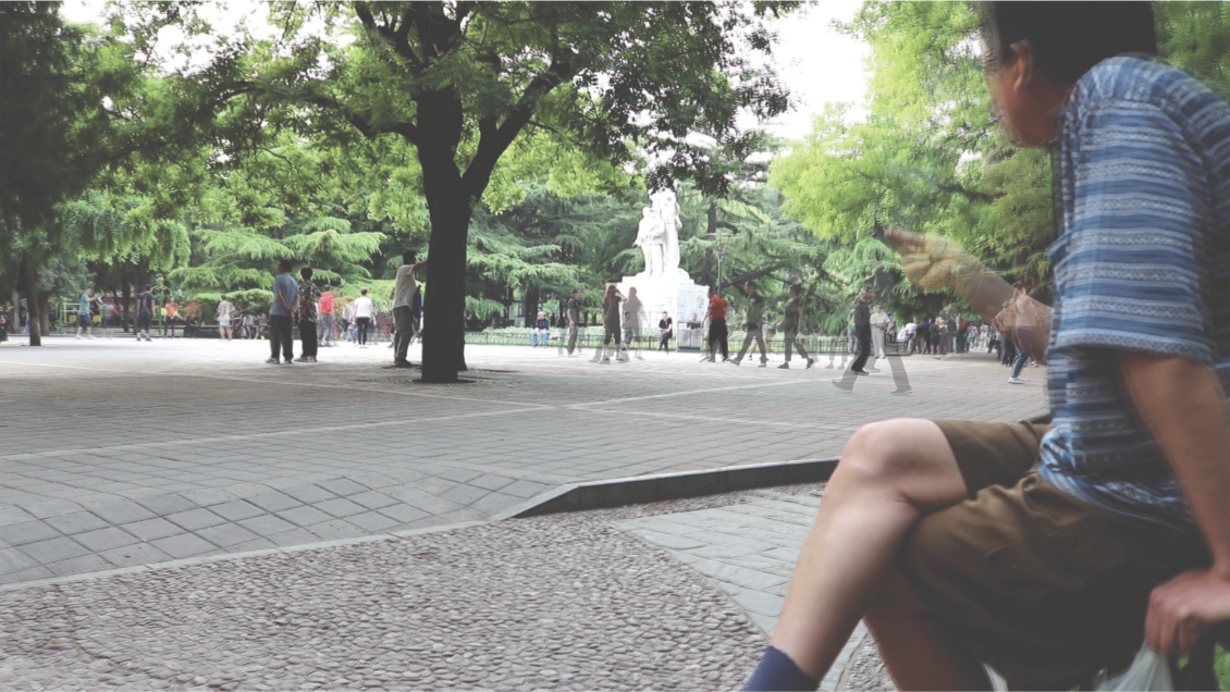 A man enjoying a cigarette and people watching at Dongdan Park in Beijing, China. Photo by: Estello Raganit.