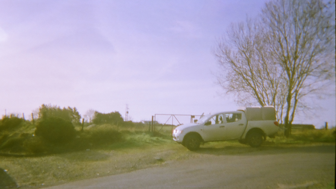 A disposable camera photo taken of a truck stopped in front of a gate on the side of the road in a small town in Northern Ireland. Photo by: Estello Raganit and Cyril Downey.