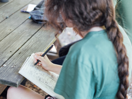 Student writes notes at Hurley Farm visit during Fall 2022 intensive.