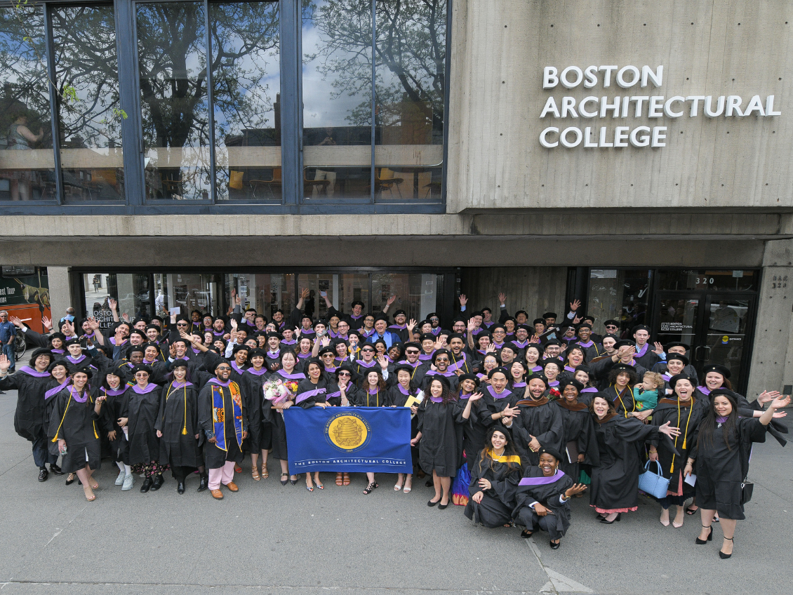 Graduates take a group photo outside the BAC 320 Newbury building.