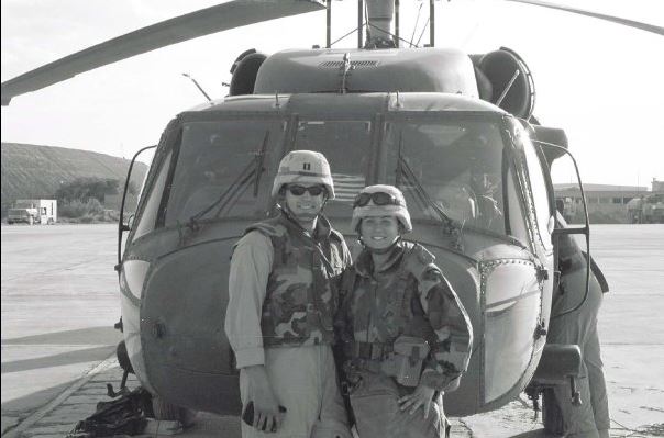 Molly Boudreau with a fellow Army member pose in front of a military helicopter in Baghdad.