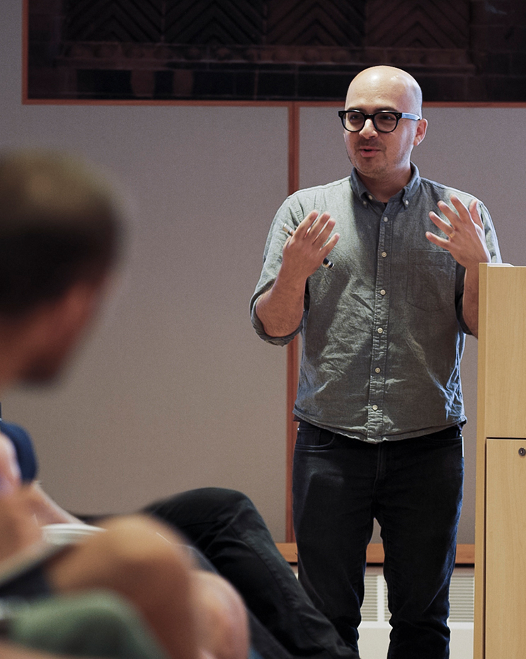 Mark Rukamathu speaks in front of a class