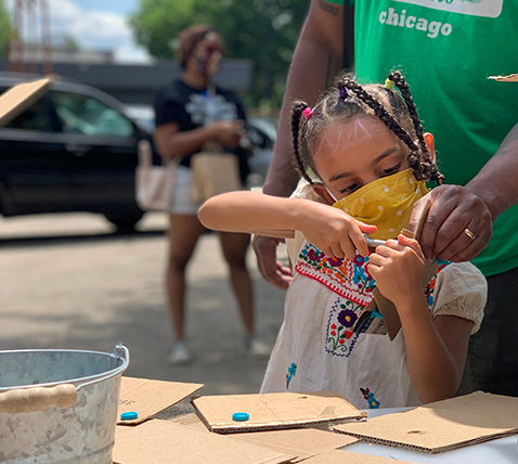 A young girl participates in a Mobile Makers event by marking on cardboard.