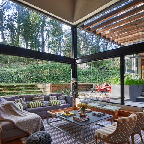 Indoor-outdoor living room with floor-to-ceiling sliding-glass doors and windows.