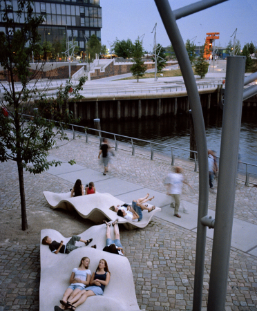 Locals enjoy lounging and walking along a public space design near the water in HafenCity, Hamburg. Copyright Alex Gaultier. Photo courtesy of Benedetta Tagliabue – EMBT Architects.