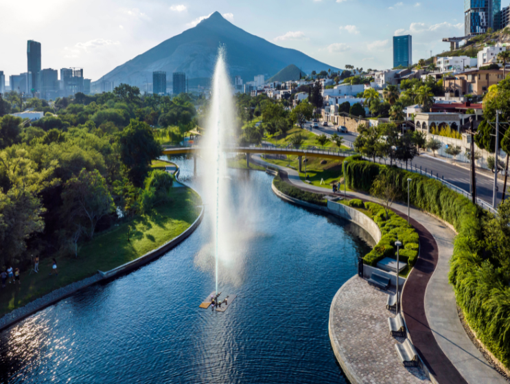 Mario Schjetnan&ndash;designed El Capit&aacute;n Park features a canal with a vertical fountain, curving paths, and urban greenery framed by Monterrey&rsquo;s mountains (aerial view).