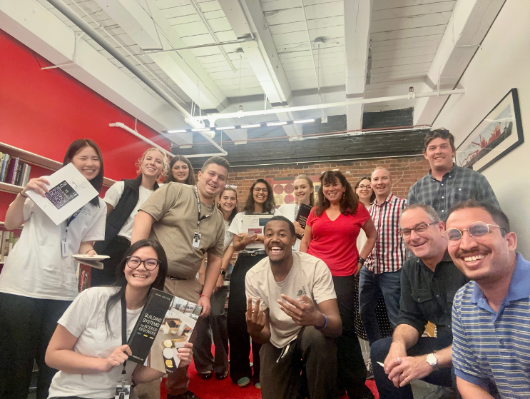 BAC students, alumni, and design professionals, including Felice and David Silverman pose together in a collaborative studio environment, highlighting community and mentorship.